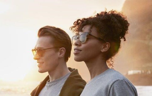 A young man and a woman on the beach wearing sunglasses